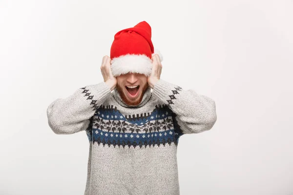 Holiday Concept - Jovem barba homem em suéter gosta de brincar com o chapéu de santa. — Fotografia de Stock