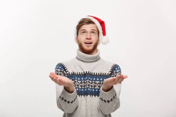 クリスマスのコンセプト-雪のジェスチャーを待っているセーターの若いクールな髭の男. — ストック写真