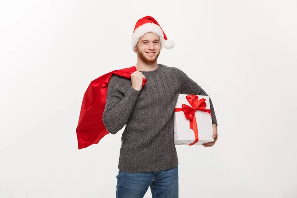 Conceito de Natal - Jovem barba feliz homem segurando saco de Papai Noel e presente branco . — Fotografia de Stock