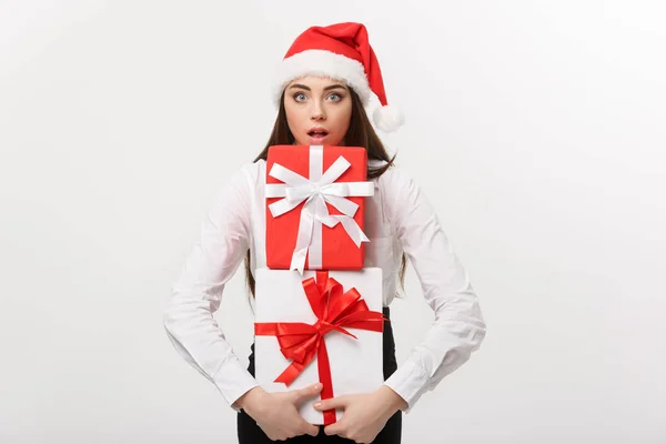 商业概念-漂亮的年轻的高加索女商人，戴着圣诞礼帽，手里拿着许多礼品盒，脸上带着意想不到的表情. — 图库照片
