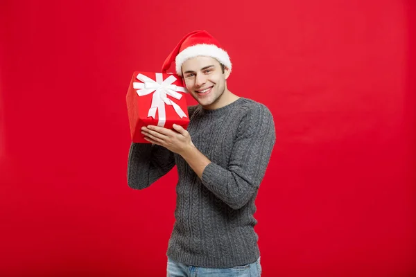 Weihnachtskonzept - schöner junger Mann im Pullover mit rotem Weihnachtsgeschenk — Stockfoto