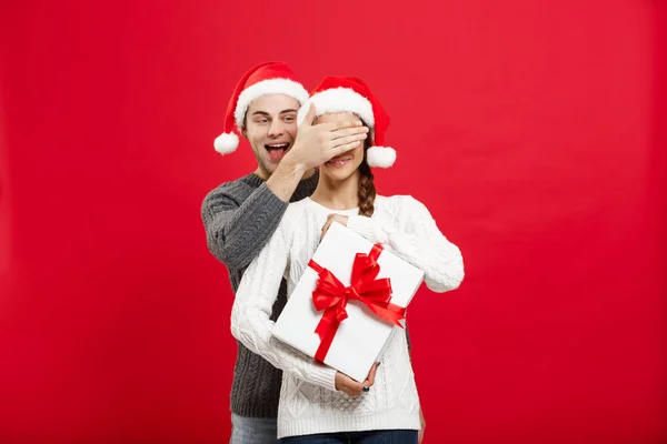 Conceito de Natal - bonito namorado jovem em suéter surpreender sua namorada com presente branco — Fotografia de Stock