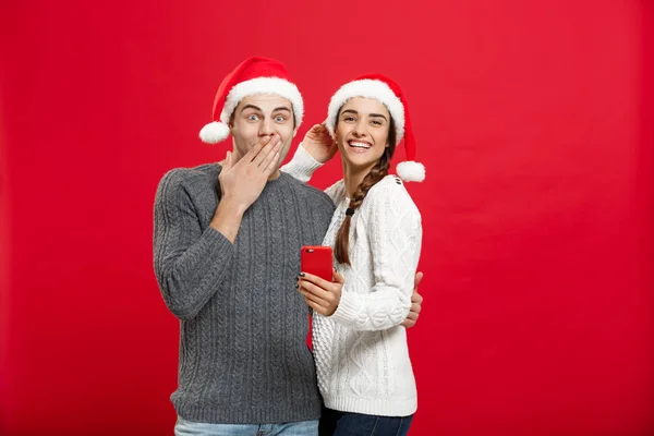 Conceito de Natal - Jovem casal bonito e bonito gosta de verificar no telefone móvel no dia de Natal — Fotografia de Stock