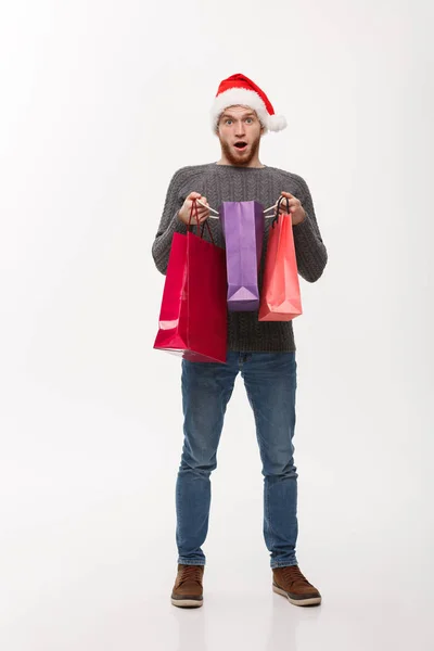 Weihnachtskonzept - attraktiver junger Kaukasier überrascht schockierendes Geschenk in Einkaufstasche. — Stockfoto