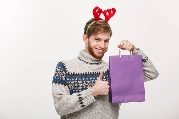 Weihnachtskonzept - junger gutaussehender Bartträger glücklich mit Einkaufstasche in der Hand. — Stockfoto