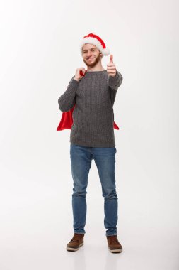 Noel kavramı - kendine güvenen genç adam holding kırmızı büyük santa çanta vererek başparmak kadar akıllı ve.