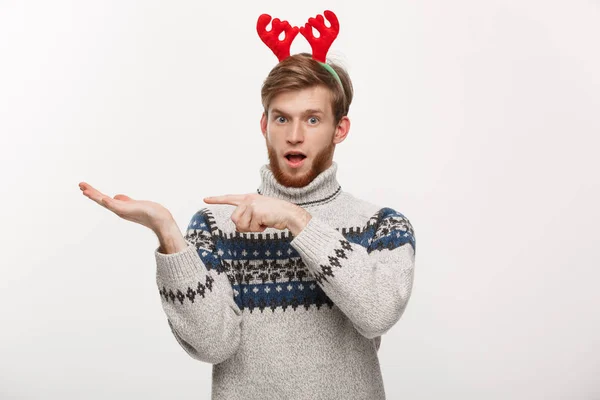 Holiday Concept - Νεαρός γενειοφόρος με πουλόβερ απολαμβάνει να παίζει και να δείχνει το χέρι στην πλευρά. — Φωτογραφία Αρχείου