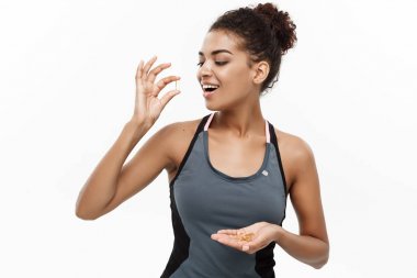 Sağlıklı ve Fitness kavramı - güzel Afrikalı-Amerikalı balık yağı hapı aldığın Closeup portresi. Beyaz stüdyo arka plan üzerinde izole.