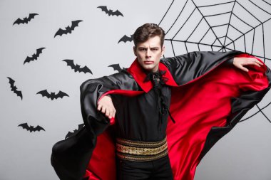 Vampir Cadılar Bayramı kavramı - yakışıklı beyaz vampir halloween kılık kırmızı, siyah hırkasını çırpınan portresi.