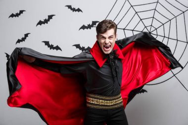 Vampir Cadılar Bayramı kavramı - yakışıklı beyaz vampir halloween kılık kırmızı, siyah hırkasını çırpınan portresi.