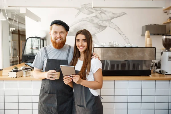 Conceito de negócio de café - felizes jovens empresários casal de pequena loja de café trabalhando e aplainando em tablet . — Fotografia de Stock