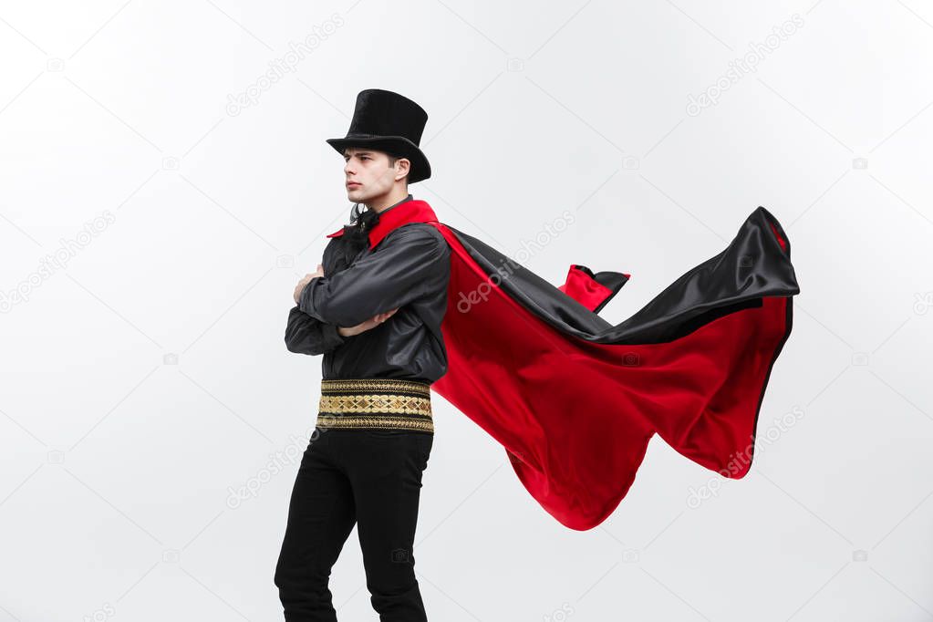 Vampire Halloween Concept - Portrait of handsome caucasian Vampire halloween costume fluttering his red, black cloak.