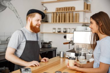 Kahve iş kavramı - genç beared yakışıklı barista modern kafede güzel beyaz müşteri ile konuşurken.