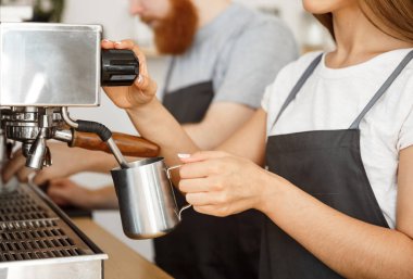 Kahve iş kavramı - Bayan barista hazırlama ve eşi dururken siparişle kahve için süt kafede Buhar önlük portresi.