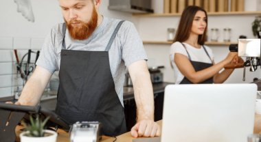 Kahve iş kavramı - sakallı yakışıklı genç barmen, barista veya sipariş dijital tablet menüsünde modern kahve dükkanında konuk ilanıyla Yöneticisi.