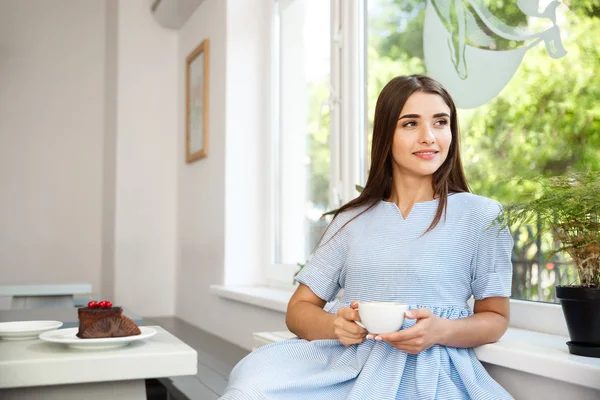 Genç güzel beyaz Bayan zevk içme ve tatlı modern kahve dükkanında öğlen sahip..