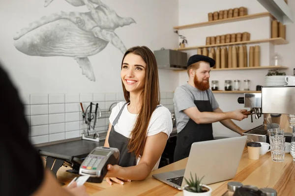 Conceito de negócio de café - Bela barista feminina dando serviço de pagamento para o cliente com cartão de crédito e sorrindo enquanto trabalhava no balcão do bar no café moderno . — Fotografia de Stock