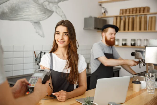 Conceito de negócio de café - Bela barista feminina dando serviço de pagamento para o cliente com cartão de crédito e sorrindo enquanto trabalhava no balcão do bar no café moderno . — Fotografia de Stock