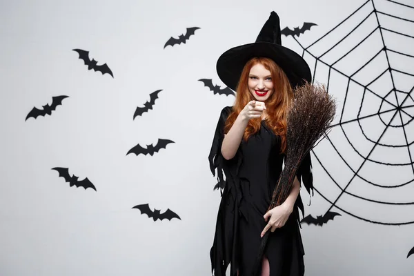 Halloween Concept - Happy elegante heks met bezem halloween wijzende vinger aan kant doen. — Stockfoto