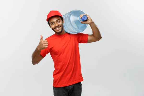 Concepto de entrega - Guapo repartidor afroamericano que sostiene el tanque de agua. Aislado en Grey studio Background. Copiar espacio . —  Fotos de Stock