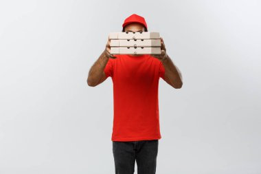 Teslimat kavramı - yakışıklı Afrikalı-Amerikalı Pizza teslimi adam geride Pizza kutuları gizleme portresi. Arka plan gri studio izole. Kopya alanı.