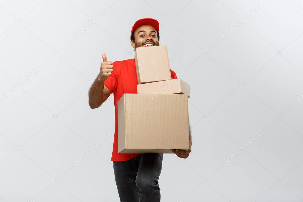 Delivery Concept - Portrait of Happy African American delivery man holding box packages and showing thumps up. Isolated on Grey studio Background. Copy Space.