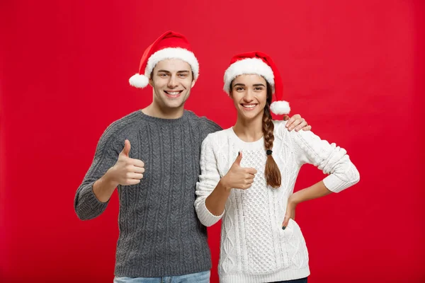 Рождественская концепция - портрет прекрасная молодая пара показывая удар вверх жест с пальцем на камеру — стоковое фото