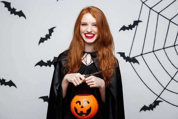 Retrato de hermosa bruja caucásica sosteniendo calabaza naranja para celebrar Halloween . — Foto de Stock