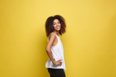 Trendy gözlüklü sarı stüdyo arka plan üzerinde ilanıyla güzel çekici Afrikalı-Amerikalı kadın. Kopya alanı.