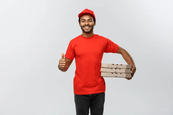 Leverans koncept - porträtt av Happy African American leverans man hålla låda paket och visar medvetslöshetsattacker. Isolerad på grå studio bakgrund. Kopiera utrymme. — Stockfoto