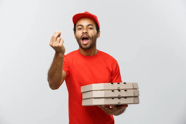 Lieferkonzept - Porträt eines glücklichen afrikanisch-amerikanischen Zustellers, der leckere Handbewegungen zeigt und Pizzakartons in der Hand hält. isoliert auf grauem Studiohintergrund. Kopierraum. — Stockfoto