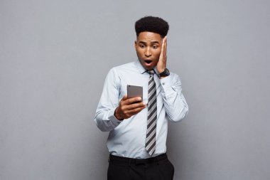 İş kavramı - mutlu yakışıklı profesyonel Afrikalı-Amerikalı işadamı şok edici bir şey üstünde hareket eden telefon ile.