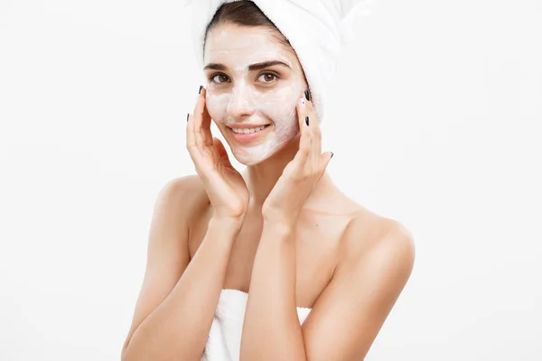 美容护肤理念-美丽的白种女人脸上的肖像应用奶油面膜在她的面部皮肤白色背景. — 图库照片