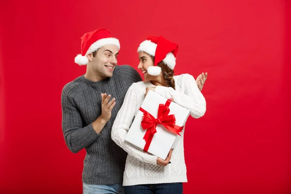 Conceito de Natal - bonito namorado jovem em suéter surpreender sua namorada com presente branco — Fotografia de Stock