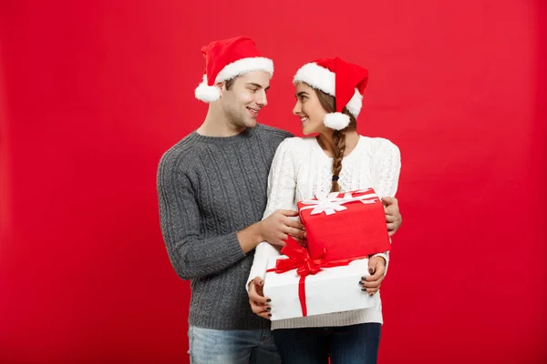 Conceito de Natal - bonito namorado jovem em camisola de Natal surpreender sua namorada com presentes — Fotografia de Stock