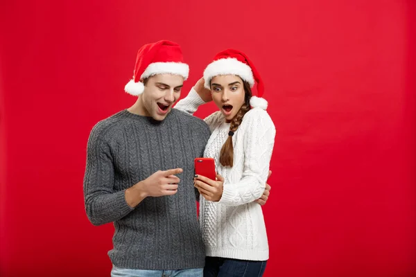 Conceito de Natal - Jovem casal bonito e bonito gosta de verificar no telefone móvel no dia de Natal — Fotografia de Stock