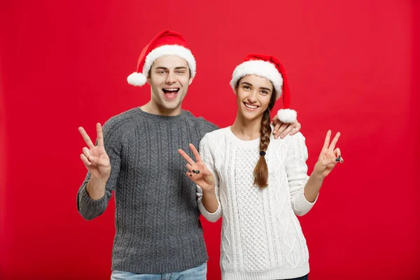 Conceito de Natal - retrato lindo jovem casal mostrando gesto de dois dedos com o dedo para câmera — Fotografia de Stock