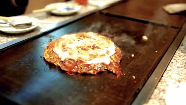 Okonomiyaki Japans eten. Pannenkoek met een verscheidenheid van ingrediënten, beslag, gemaakt van meel en water, gesnipperde kool, ei, ui en zeevruchten. — Stockvideo