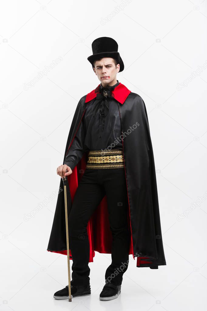 Vampire Halloween Concept - Full lenght Portrait of handsome caucasian Vampire in black and red halloween costume. 