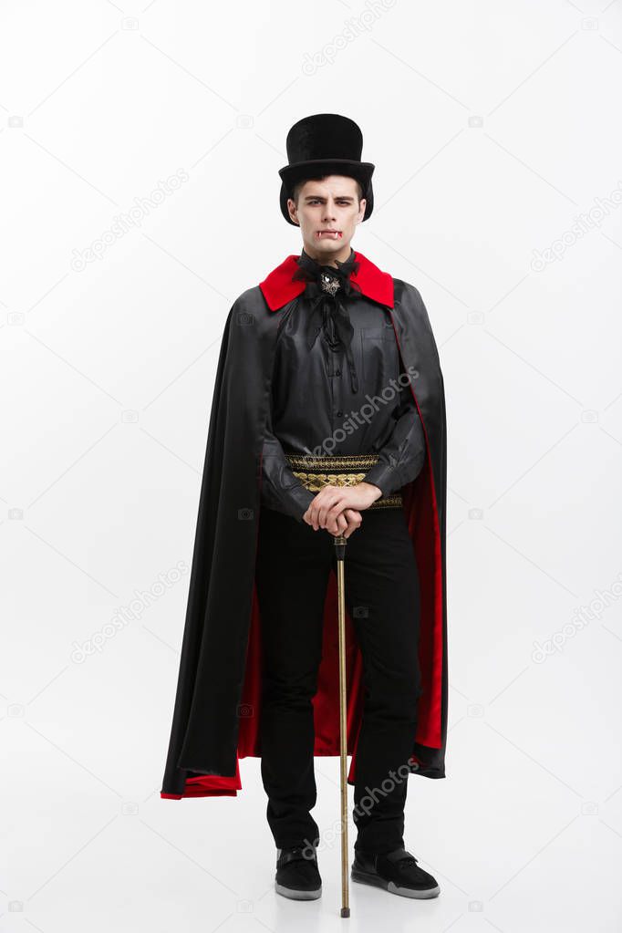 Vampire Halloween Concept - Full length Portrait of handsome caucasian Vampire in black and red halloween costume. 