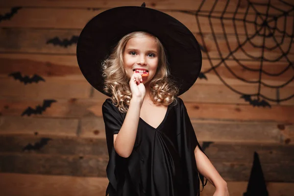 Halloween cadı kavramı - küçük cadı Cadılar Bayramı tatlı çocukla ve neşeli gülümseyen şeker. yarasa ve örümcek web arka plan üzerinde. — Stok fotoğraf
