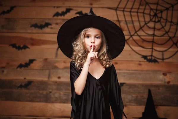 Koncepcja Halloween Witch - strzał zbliżenie małe dziecko kaukaski czarownica, trzymając palec na ustach, prosząc o ciszę. — Zdjęcie stockowe