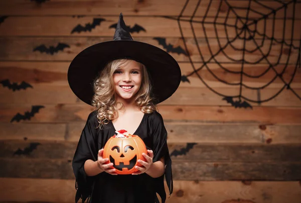 Koncepcja Witch Halloween - małe dziecko kaukaski czarownica cieszyć się z halloween dynia słoik. bat i spider web tle. — Zdjęcie stockowe