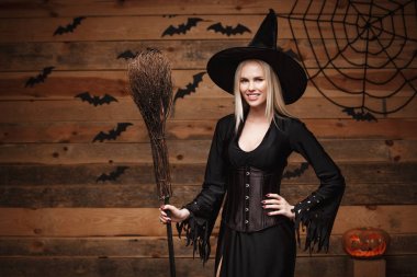 Halloween cadı kavramı - mutlu Cadılar Bayramı seksi cadı eski ahşap studio arka plan üzerinde poz holding.
