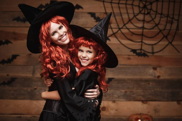 Halloween Concept - Bella madre caucasica e sua figlia con lunghi capelli rossi in costumi da strega felici sorridenti e si abbracciano . — Foto Stock