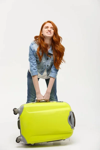 Reise- und Lifestylekonzept: Junge Frau leidet unter Rückenschmerzen beim Heben eines schweren Koffers auf gelbem Hintergrund — Stockfoto