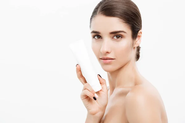 Güzellik gençlik cilt bakım kavramı - güzel beyaz kadın yüz tutan ve krem tüp ürün sunma portre. Beyaz arka plan üzerinde güzel Spa modeli mükemmel taze temiz ten kızla.
