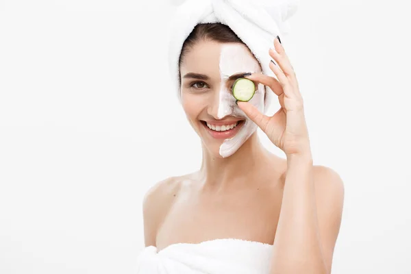 美容美发青春肌肤护理理念- -美容美发的白人女性在脸上涂上乳霜，并拿着新鲜黄瓜。. — 图库照片