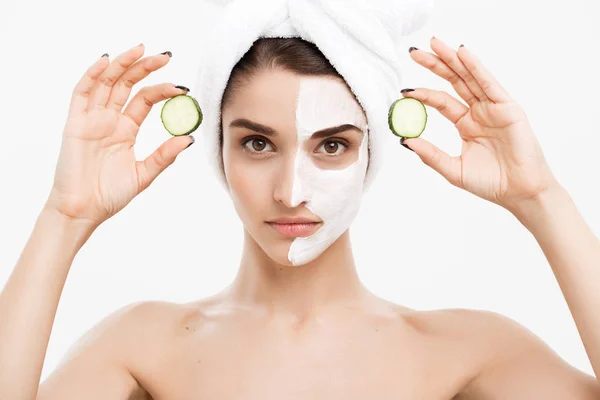 美容美发青春肌肤护理理念- -美容美发的白人女性在脸上涂上乳霜，并拿着新鲜黄瓜。. — 图库照片