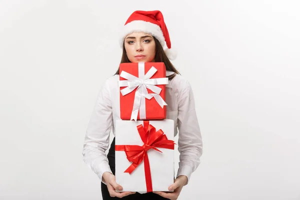 Business Concept - Beautiful young caucasian business woman with santa hat holding a lot of gift boxes with worry facial expression. — Stock Photo, Image